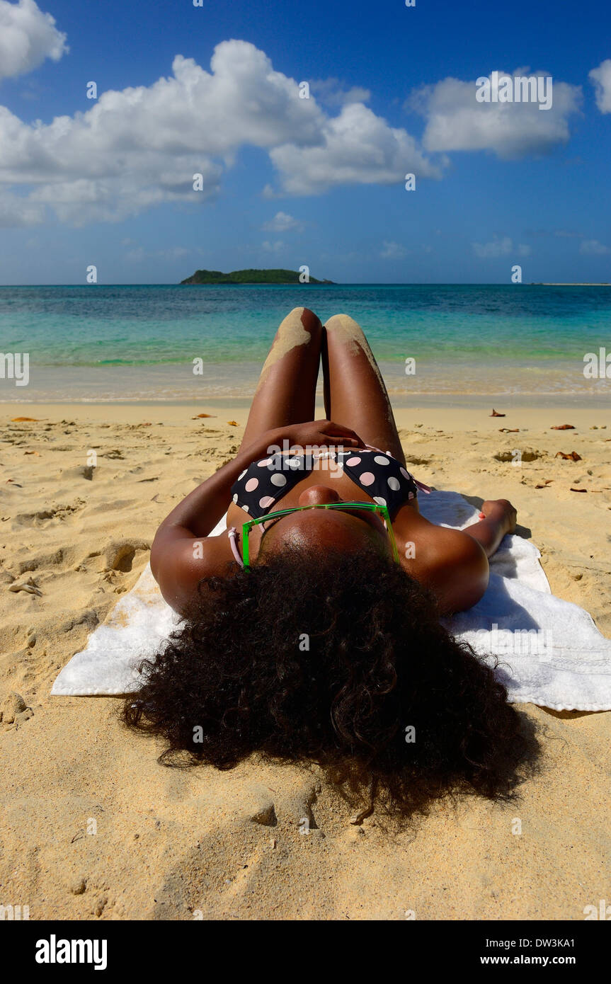 Una donna a prendere il sole sulla spiaggia Paradise Beach. Isola di Carriacou, Grenadine. Grenada Foto Stock
