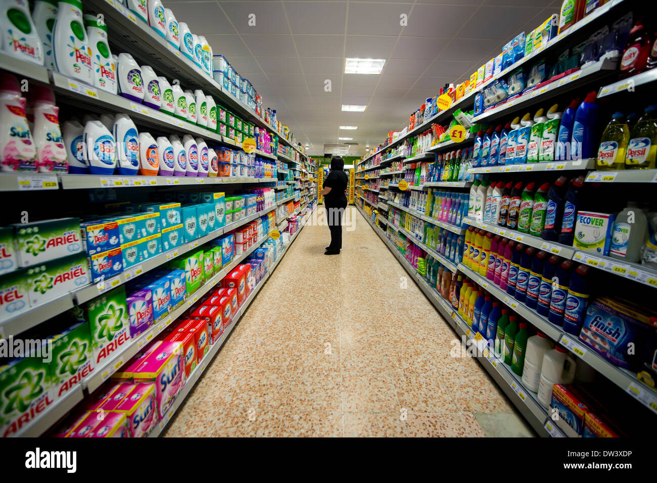 Fornitissimo isola in un supermercato. Un membro del personale osserva i ripiani per possibile ri calza Foto Stock