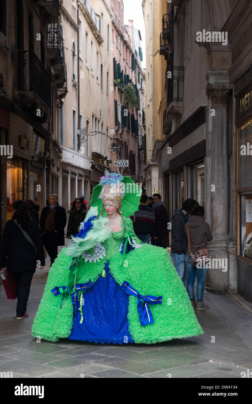 Venezia, Italia. Il 26 febbraio 2014. Sullo sfondo di una Venezia vicoli del proprio di San Marco (Piazza San Marco) questa signora pone nel suo magnifico verde e azzurro vestito con gondola e rabboccato parrucca. Venezia Carnivale - Mercoledì 26 Febbraio. Credito: MeonStock/Alamy Live News Foto Stock