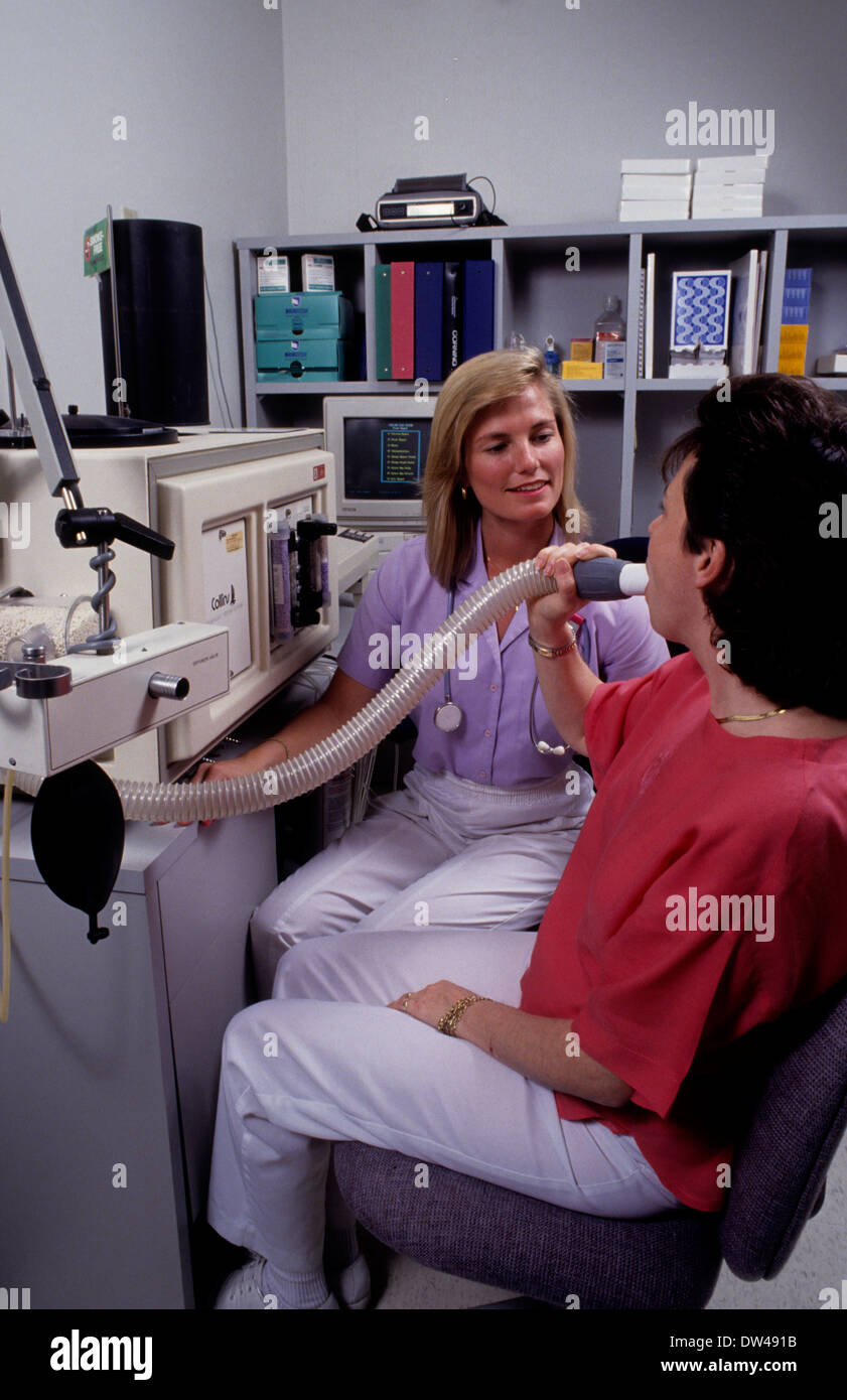 L'infermiera tech dando respiro woan capacità polmonare test di respirazione per computer in ufficio Foto Stock