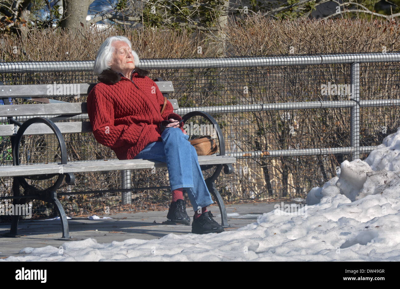 Poco dopo una tempesta di neve, una donna sunbathes su un freddo inverno pomeriggio sul lungomare di Coney Island Brooklyn, New York. Foto Stock