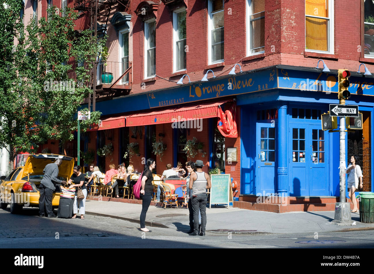 Scena di strada di persone camminare vicino a diners di gustare la cena e drink presso l'Orange Bleue in SoHo. L'Orange Bleue in SoHo Foto Stock