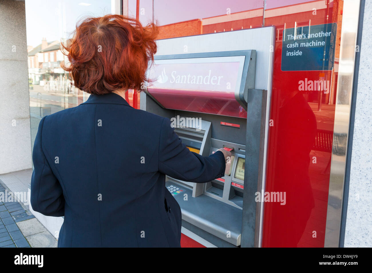 Persona inserendo una carta in un bancomat presso una banca Santander per fare un ritiro di contanti, Nottinghamshire, England, Regno Unito Foto Stock
