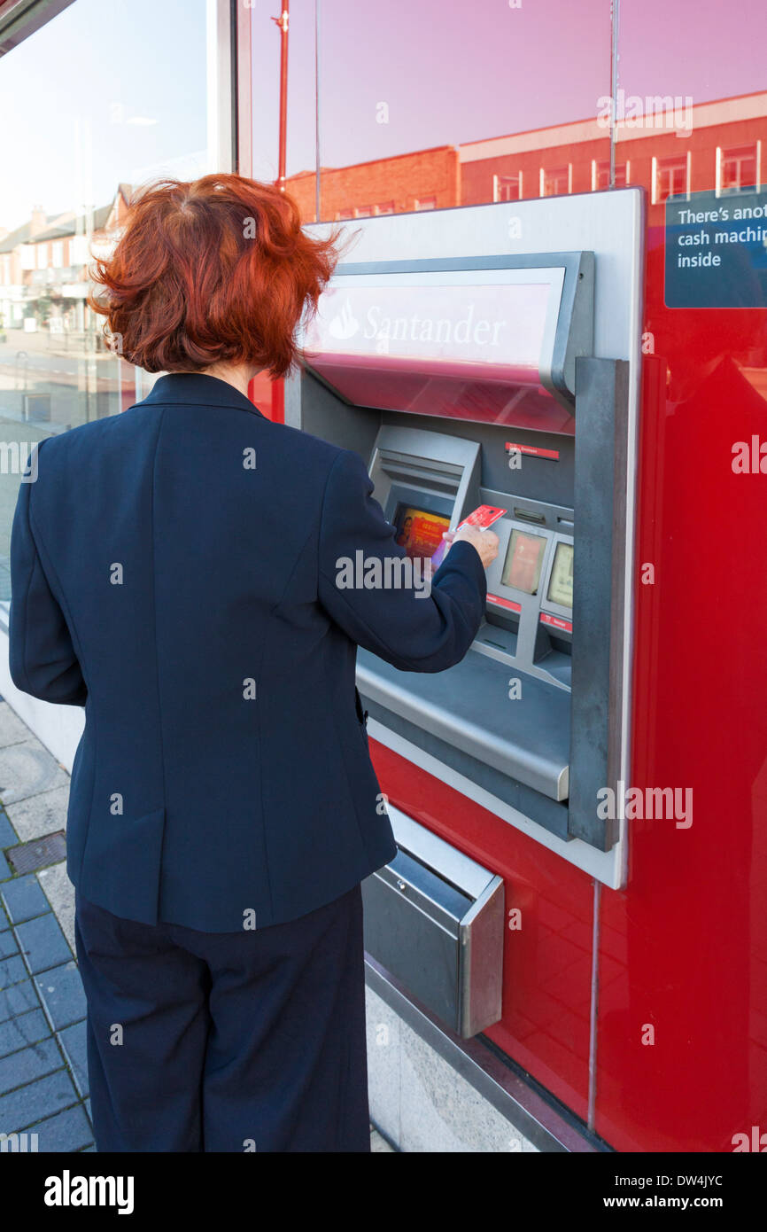 Donna mettendo la sua carta di credito in un Santander bancomat, Nottinghamshire, England, Regno Unito Foto Stock