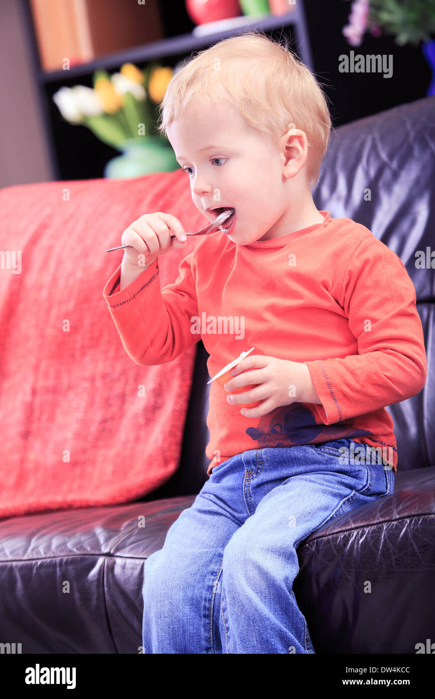 Un ragazzino di mangiare lo yogurt a casa Foto Stock