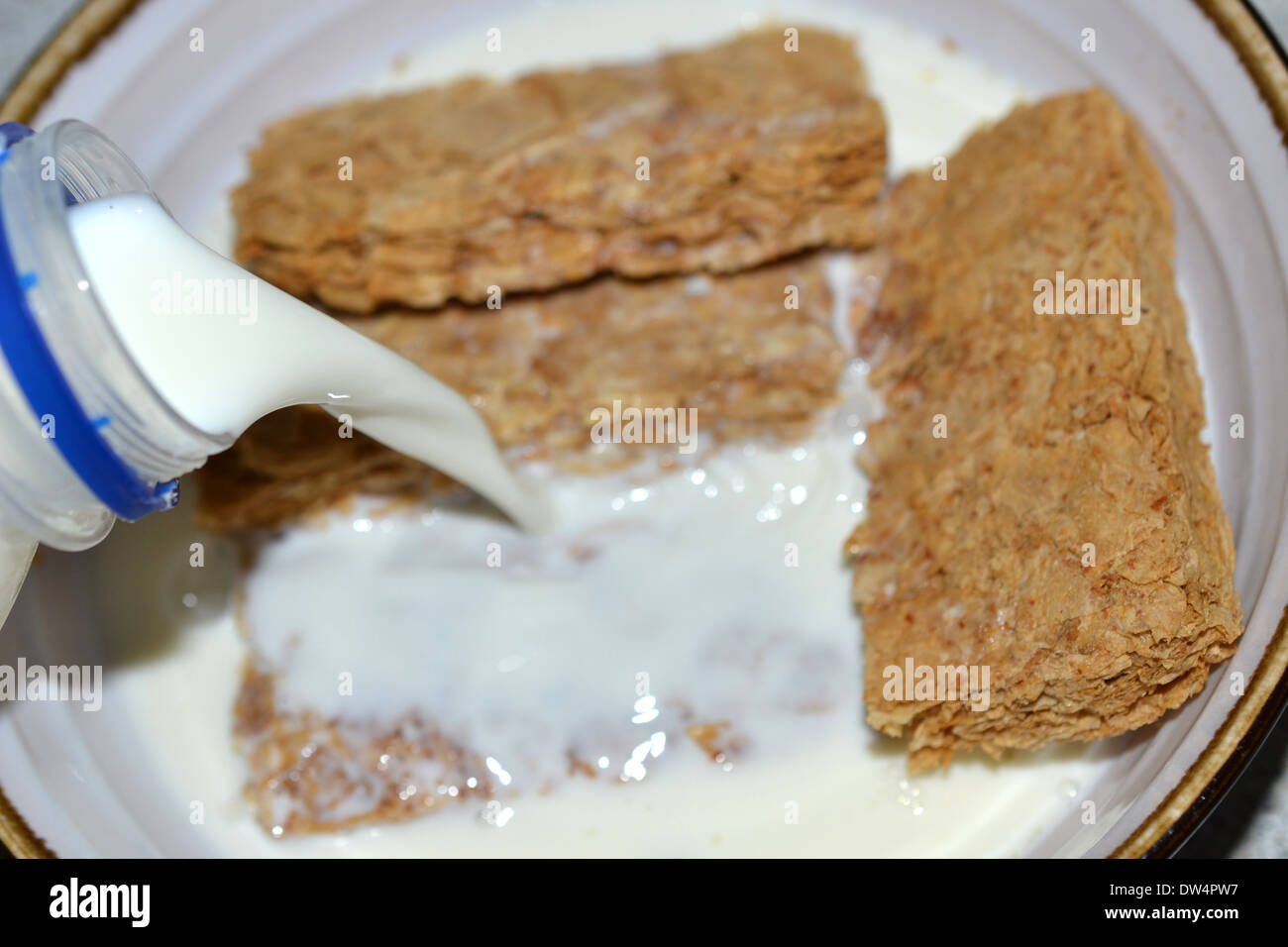 Versare il latte in una ciotola di weet-bix Foto Stock