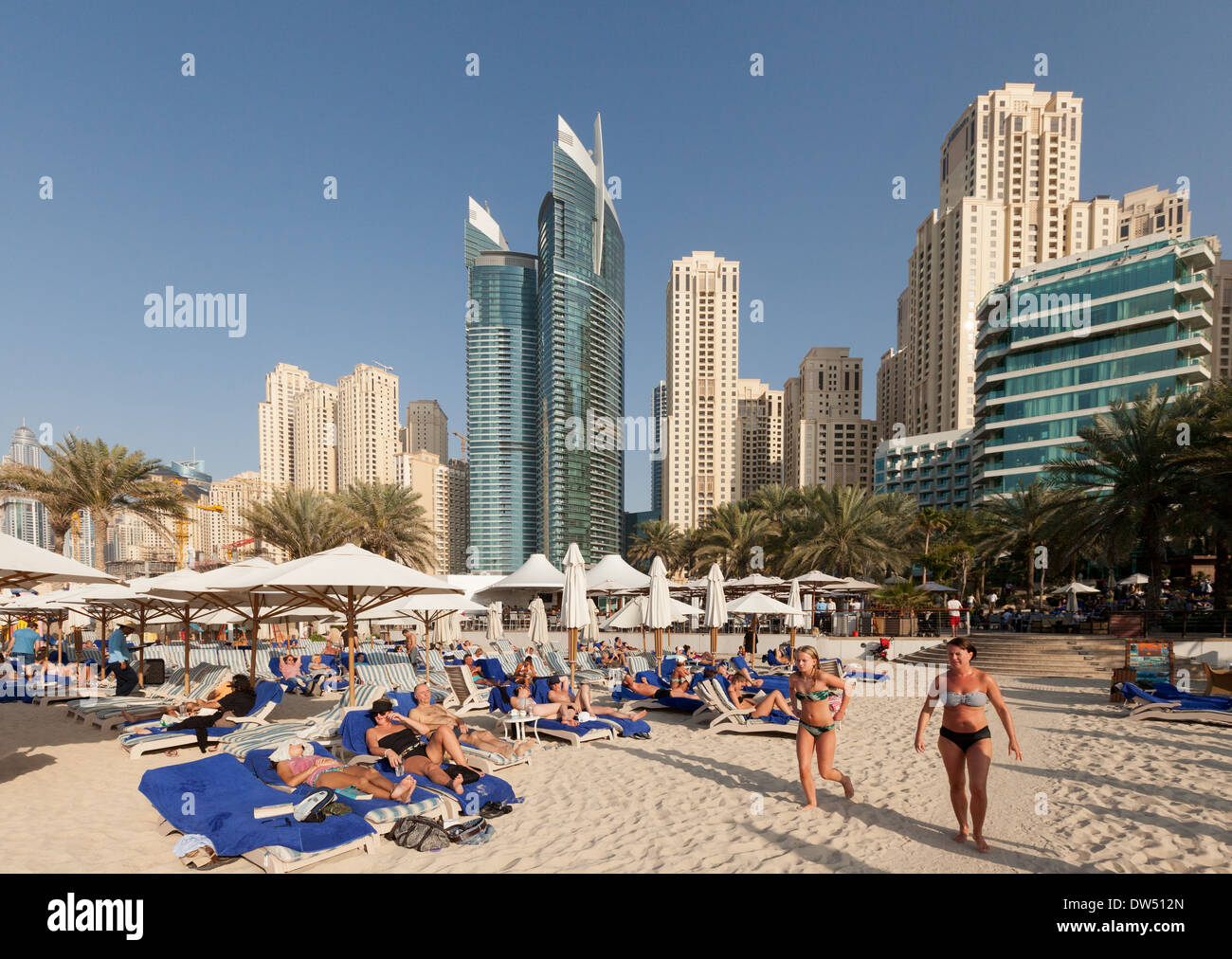 Spiaggia di Dubai; la folla di turisti in vacanza a prendere il sole sulla spiaggia di Jumeirah in inverno, Hilton Hotel, Dubai, Emirati Arabi Uniti, Emirati Arabi Uniti, Medio Oriente Foto Stock