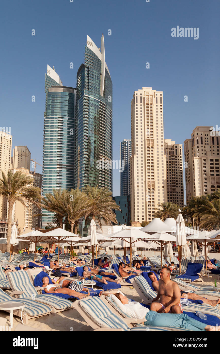 La folla di turisti in vacanza a prendere il sole sulla spiaggia di Jumeirah in inverno , Dubai, Emirati Arabi Uniti, Emirati Arabi Uniti, Medio Oriente Foto Stock