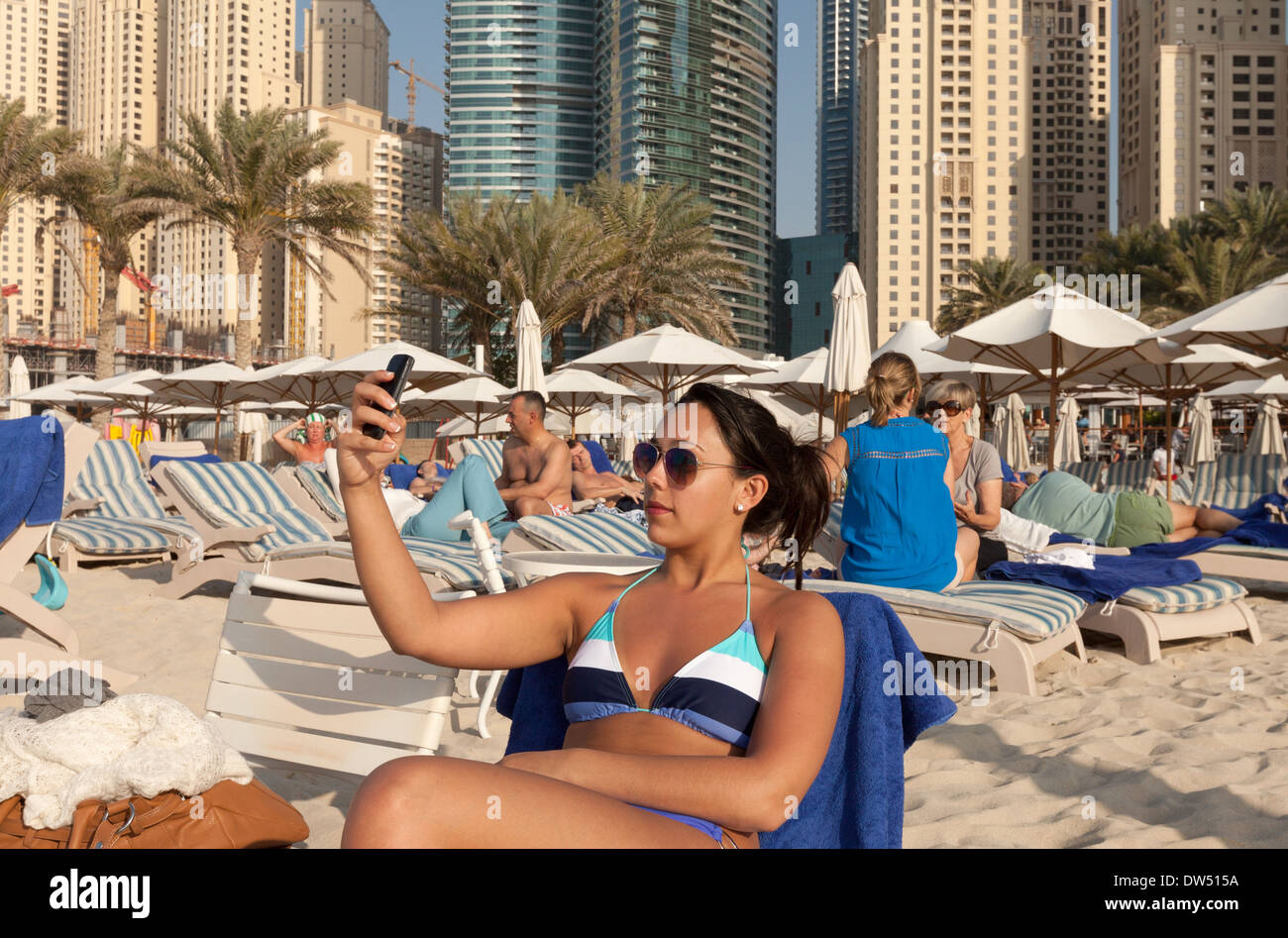Giovane donna età di età compresa tra 20s tenendo un selfie foto sulla spiaggia, spiaggia di Jumeirah, Dubai, Emirati Arabi Uniti, Emirati arabi del Medio Oriente Foto Stock