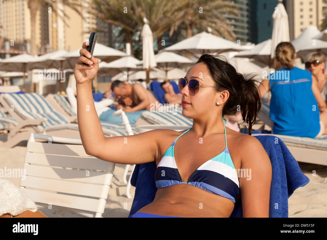 Giovane donna età di età compresa tra 20s tenendo un selfie foto sulla spiaggia, spiaggia di Jumeirah, Dubai, Emirati Arabi Uniti, Emirati arabi del Medio Oriente Foto Stock