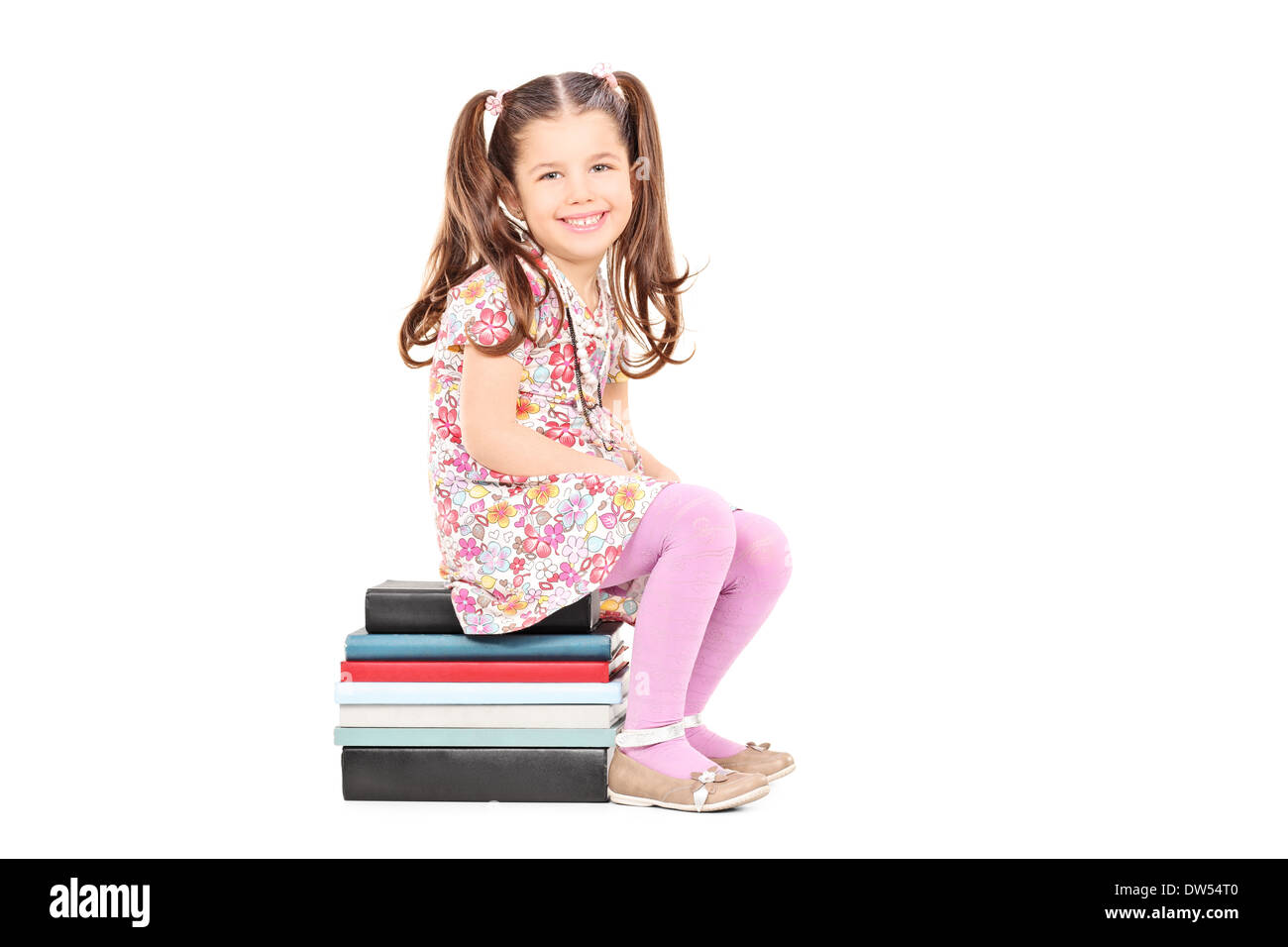 Timida ragazza seduta su una pila di libri Foto Stock