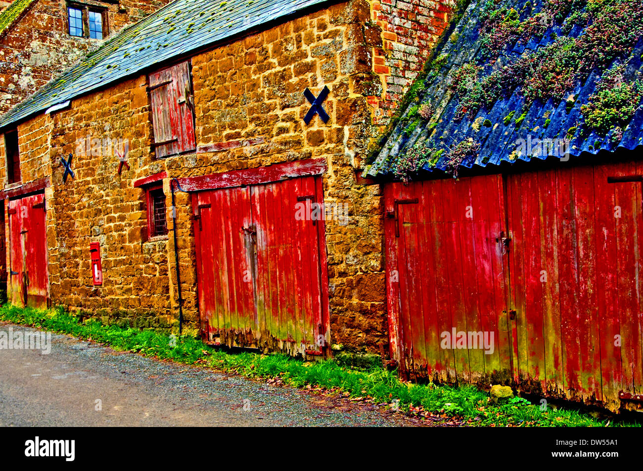 Edifici in pietra e fienile con sbiadito vernice rossa su porte. Foto Stock