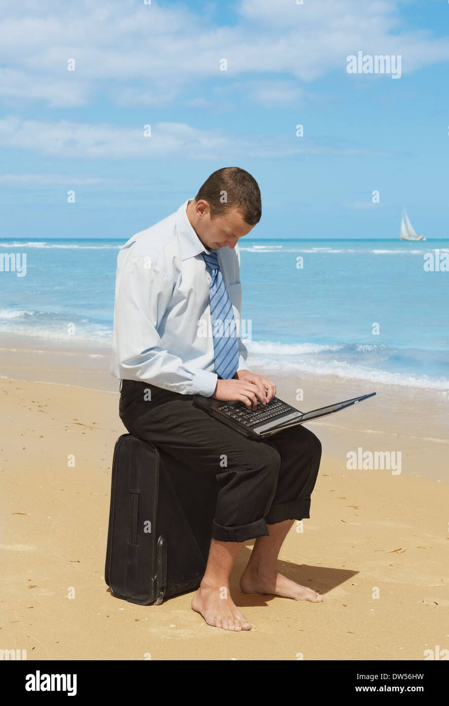 Giovane imprenditore lavora con il computer portatile sulla spiaggia Foto Stock