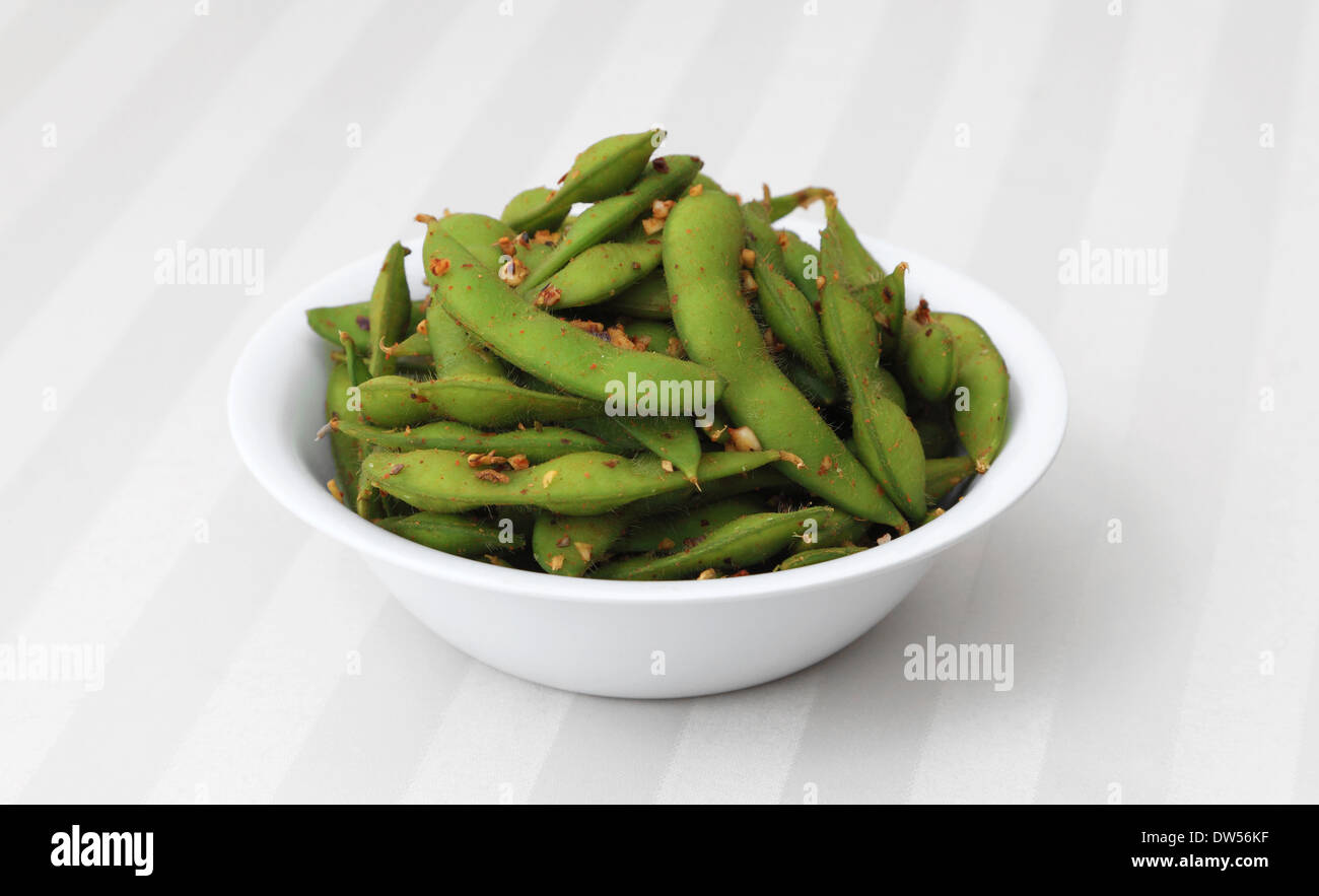Edamame piccante - cotte e speziato baccelli di fagioli di soia in una ciotola bianco. Foto Stock