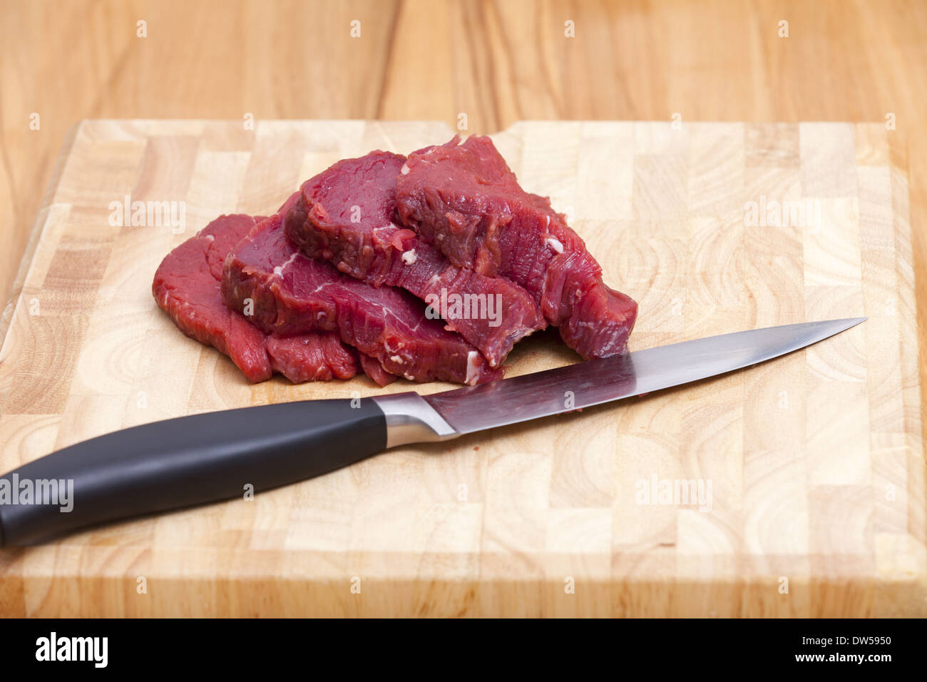 Quattro Slice materie il filetto di manzo giace su un tagliere con un coltello da cucina Foto Stock