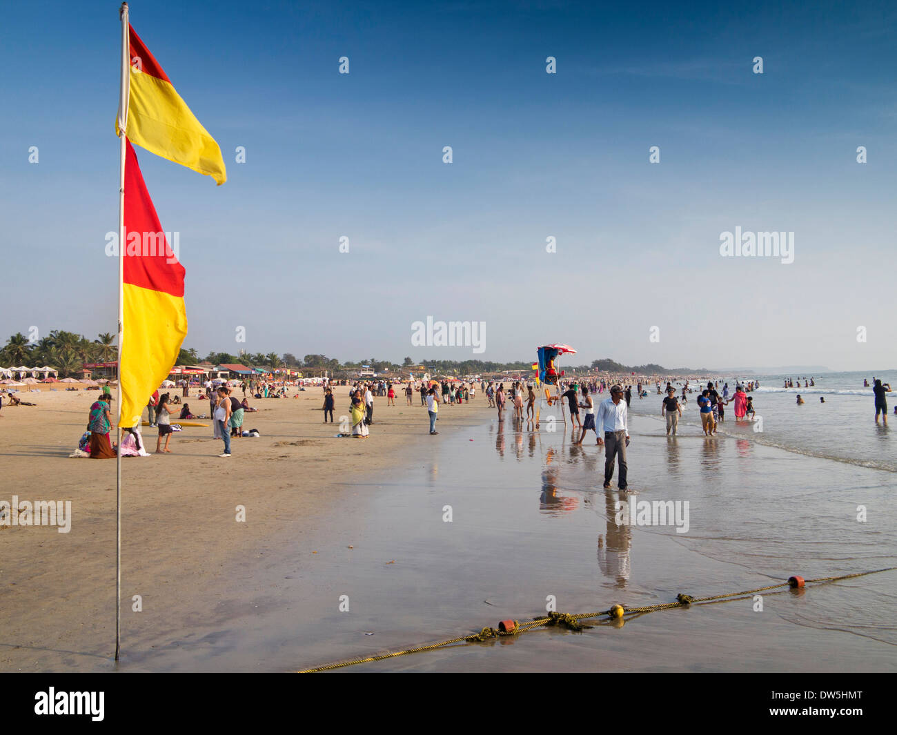 India, Goa, Baga, Indiano turisti sulla spiaggia, bagnino tra la balneazione bandiere Foto Stock