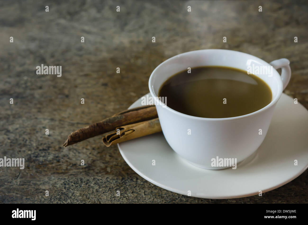 Caffè caldo con bastoncini di cannella su sfondo di legno Foto Stock