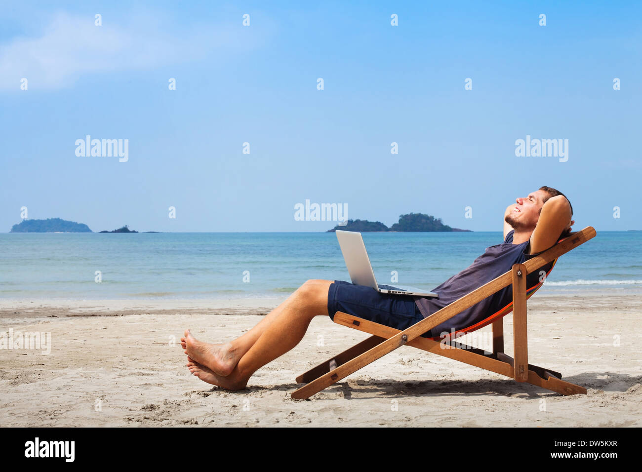 Felice uomo d affari con computer portatile rilassante sulla spiaggia Foto Stock