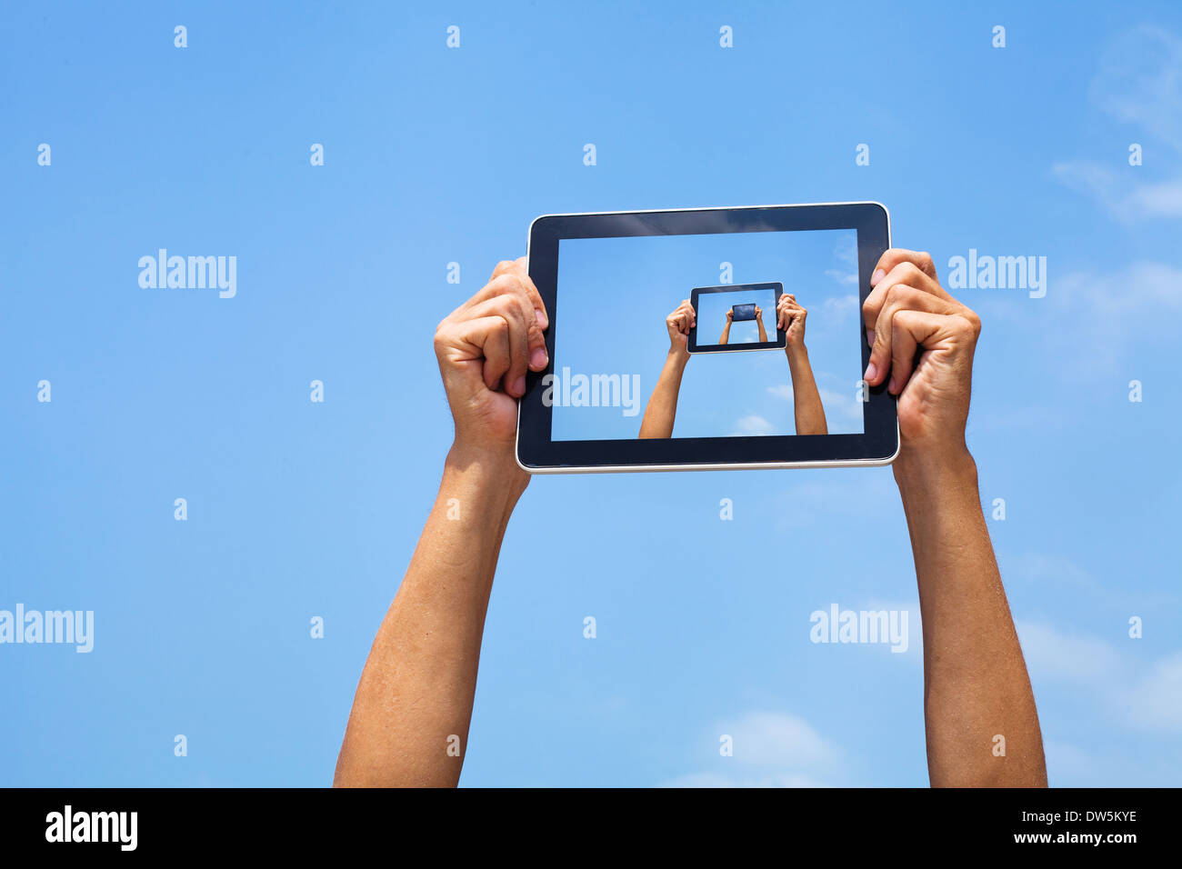 Mani tenendo compressa in cielo blu Foto Stock
