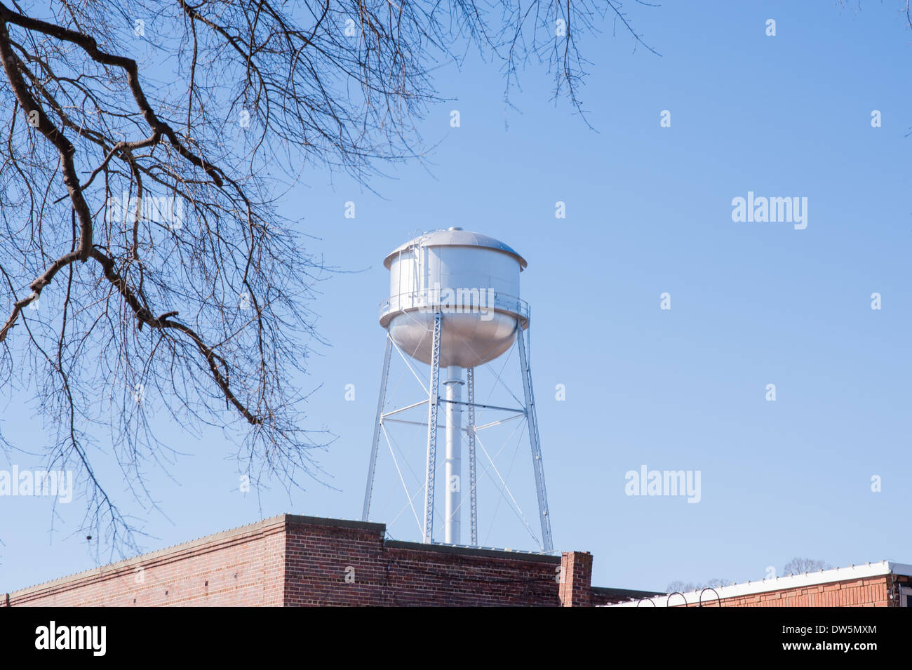 Torre di acqua su vecchi edifici in mattoni su un cielo blu chiaro giorno Foto Stock
