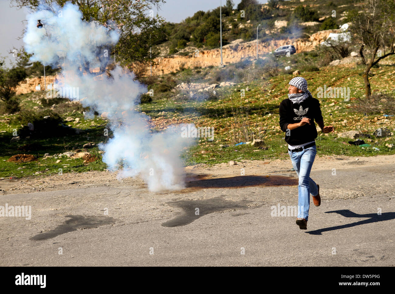 Birzeit, West Bank, Palestina - 28 Febbraio 2014: una gioventù palestinese getta pietre contro soldati israeliani durante scontri al checkpoint di Atara, a nord della Cisgiordania città di Ramallah. Gli scontri scoppiati venerdì dopo il funerale di Muataz Washaha, che è stato ucciso dalle forze israeliane giovedì nella sua casa nella West Bank village di Birzeit, nei pressi di Ramallah. (Foto di Abdalkarim Museitef/Pacific Press/Alamy Live News) Foto Stock