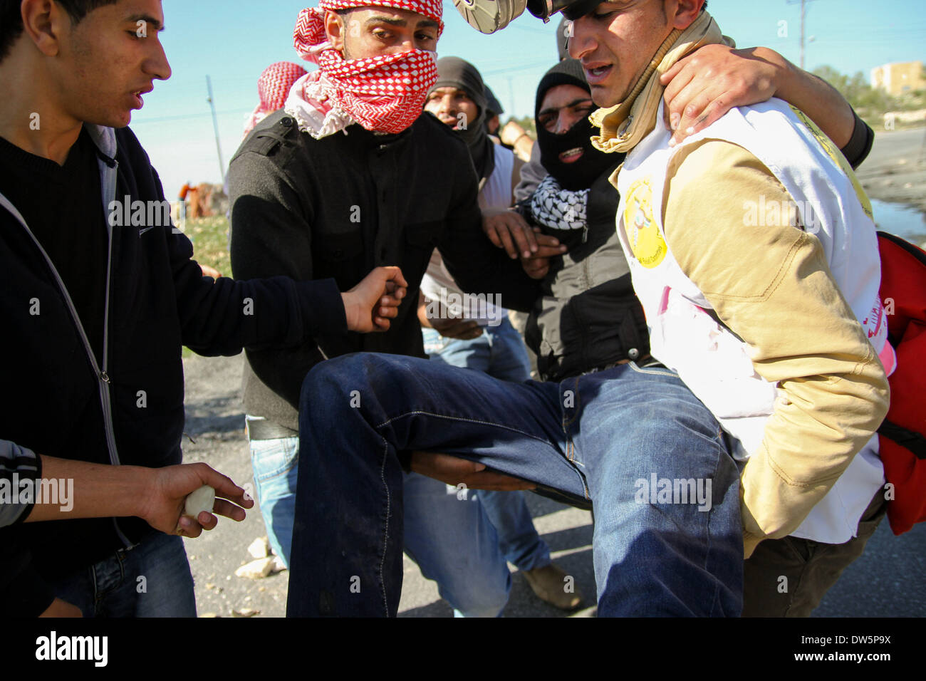 Birzeit, West Bank, Palestina - 28 Febbraio 2014: dimostranti palestinesi trasferiti giovane uomo dopo che è stato girato in piedi con l'occupazione israeliana esercito, durante scontri al checkpoint di Atara, a nord della Cisgiordania città di Ramallah . Gli scontri scoppiati venerdì dopo il funerale di Muataz Washaha, che è stato ucciso dalle forze israeliane giovedì nella sua casa nella West Bank village di Birzeit vicino a Ramallah. (Foto di Abdalkarim Museitef/Pacific Press/Alamy Live News) Foto Stock