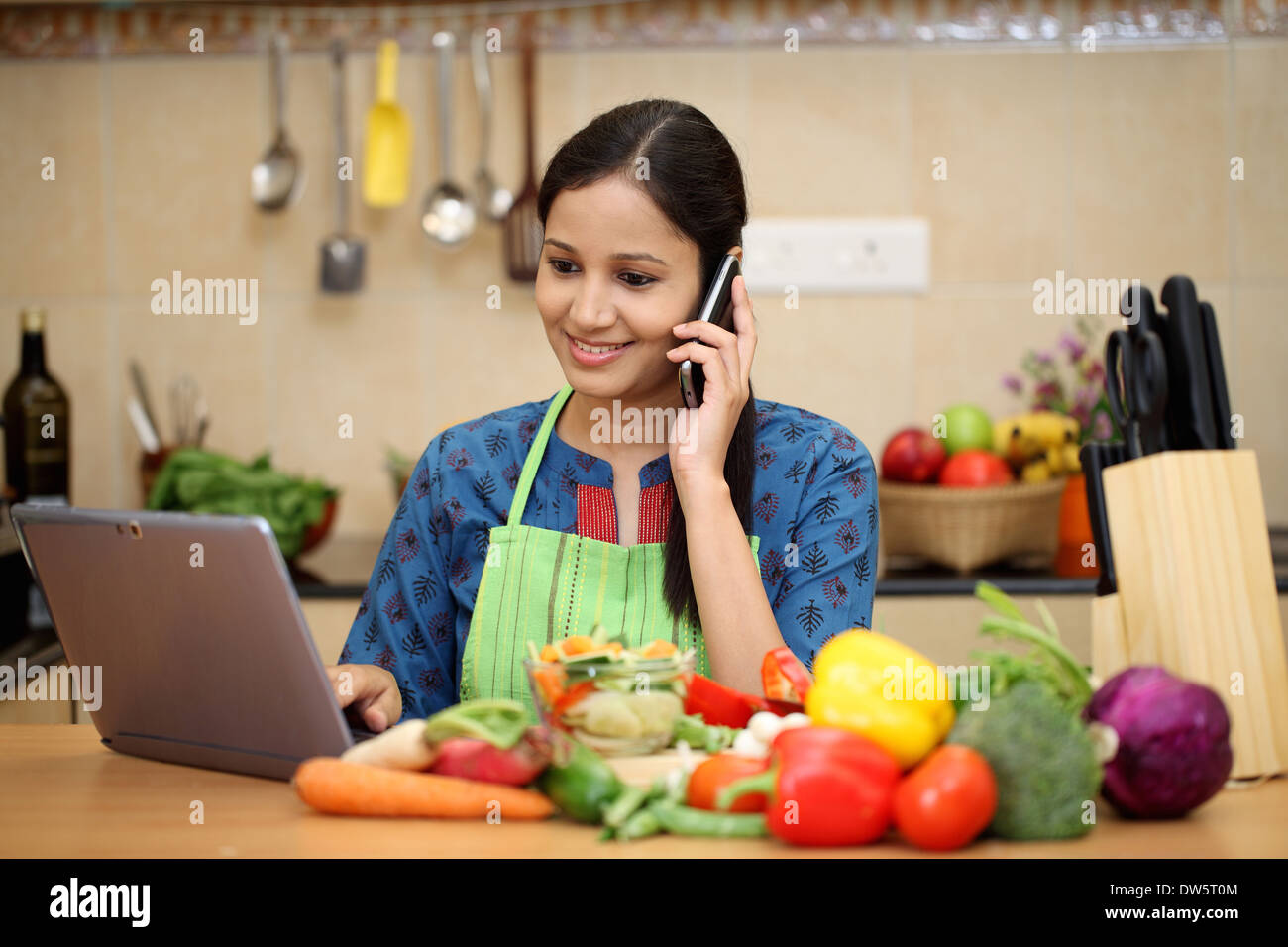 Giovane donna indiana che lavora con il tablet e parlando al cellulare Foto Stock