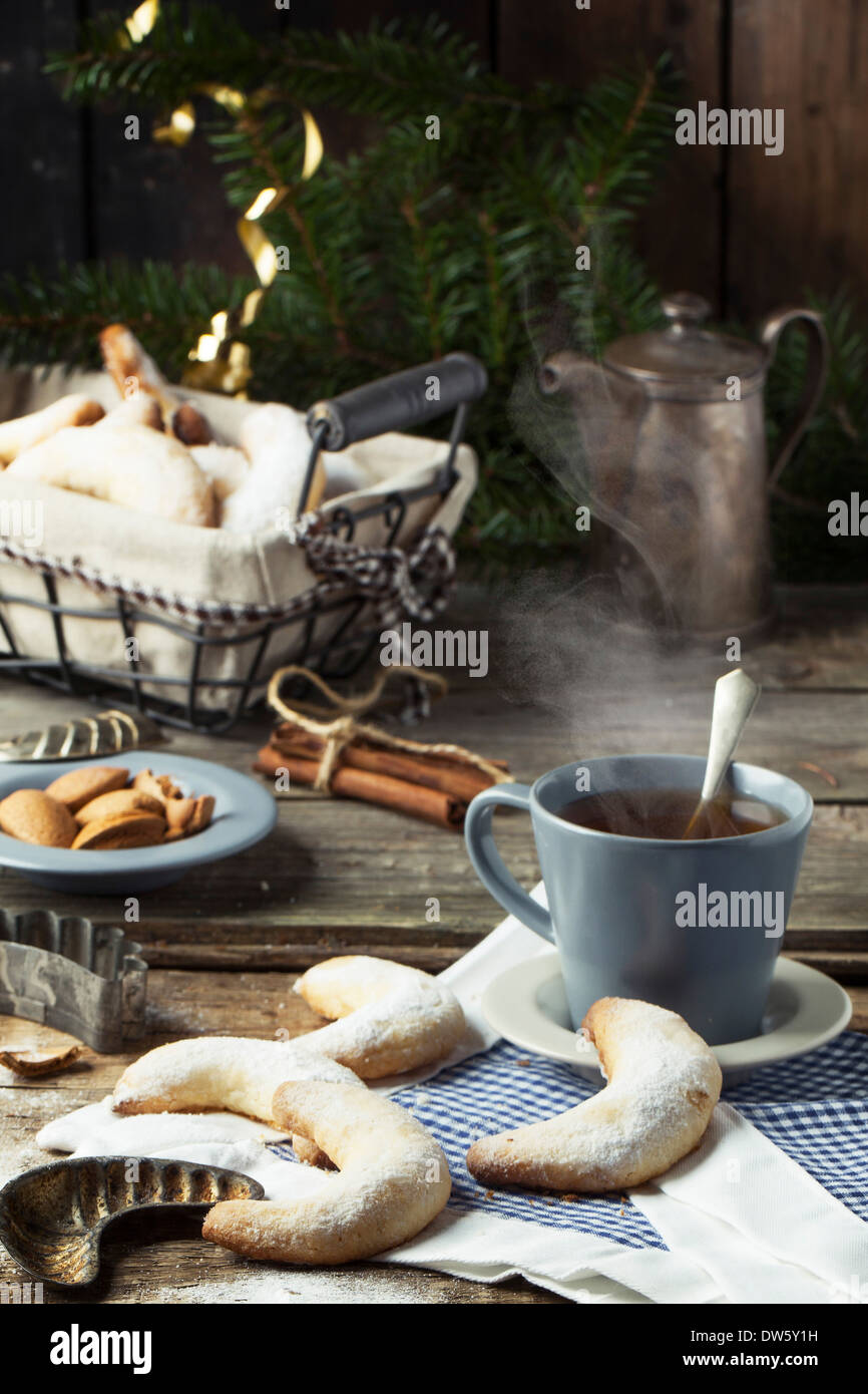 Lo zucchero in casa cookie crescent servita con tazza di tè, vintage accessori, mandorle e spezie su un vecchio tavolo in legno Foto Stock