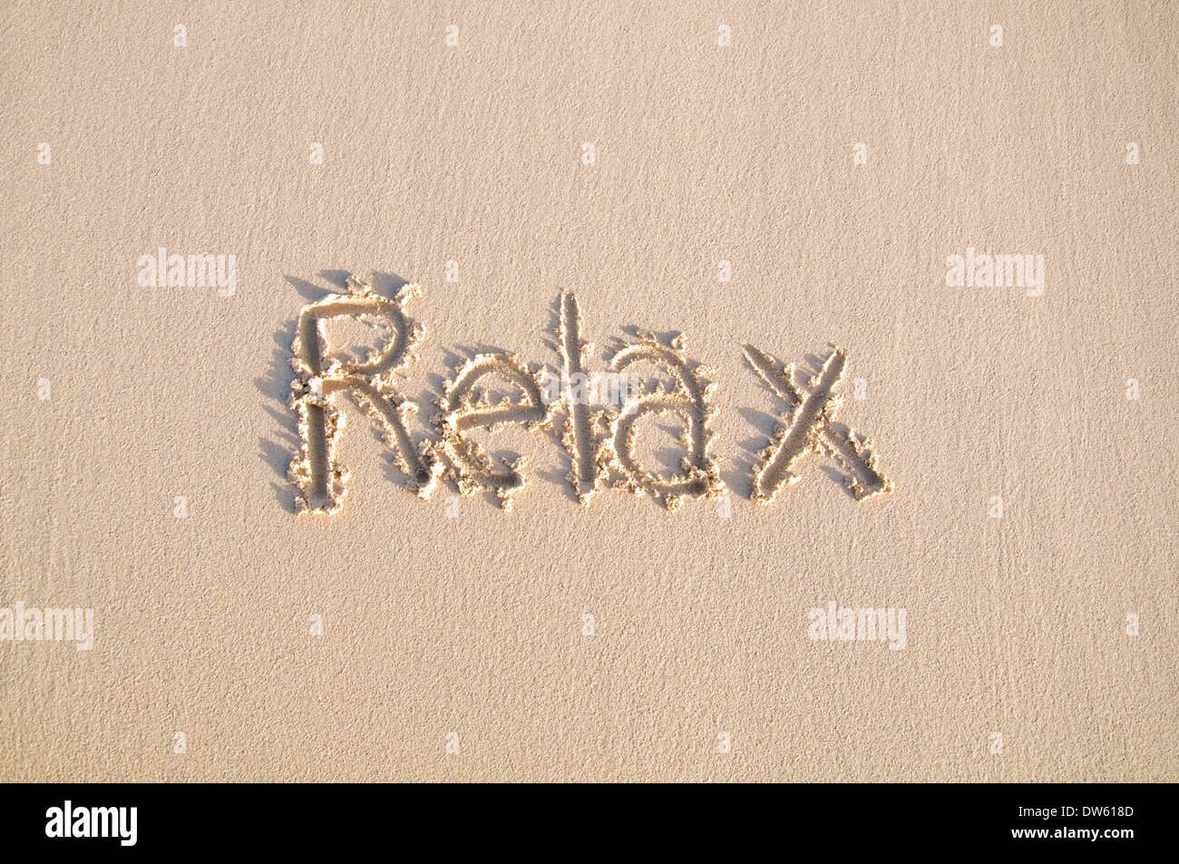 La parola "Relax" scritto su una spiaggia di sabbia. Foto Stock