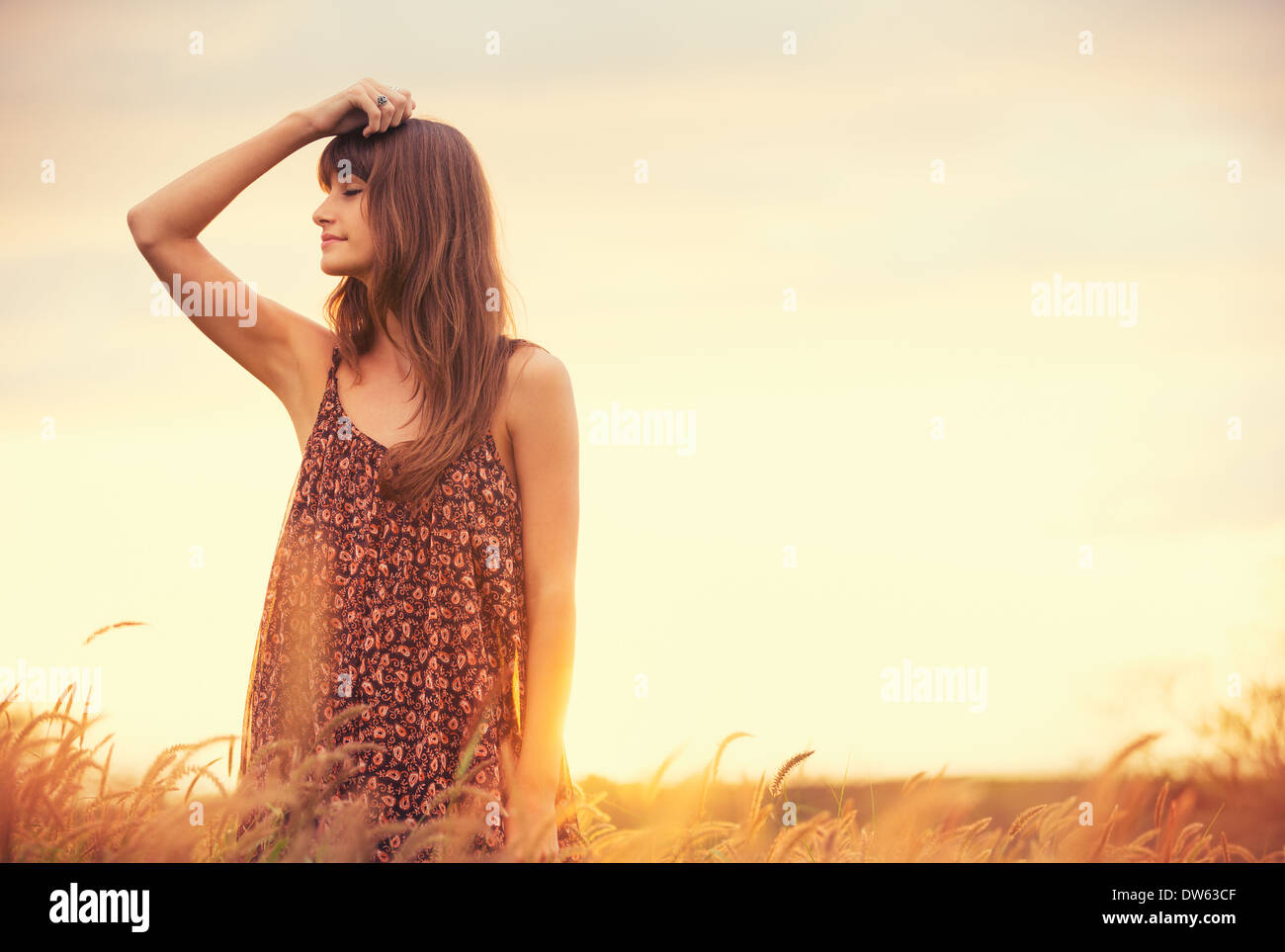 Bella donna nel campo oro al tramonto, fashion lifestyle, colori brillanti, Retroilluminato toni caldi Foto Stock