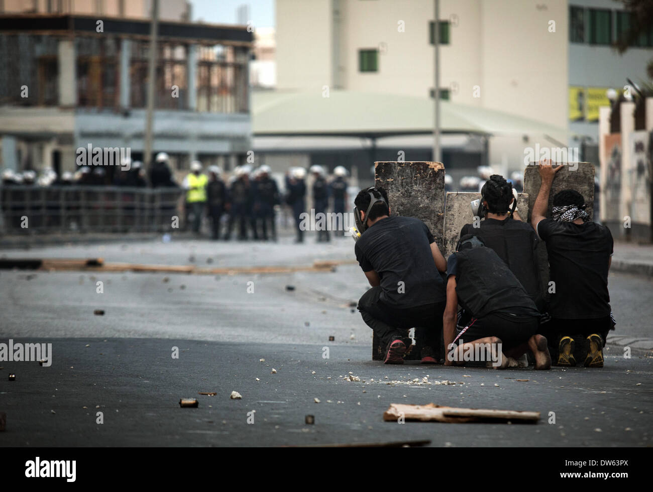 AlDaih, Bahrain - 28 Febbraio 2014: Bahraini manifestanti rifugiandosi dietro uno schermo durante scontri pesante dopo la soppressione della marcia funebre del martire (Jafar Alderazi 23 anni) nella barriera di età dei suoi genitori Venerdì, 1 marzo 2014 - La Jaafar era morto nel febbraio 27, 2014 di complicanze della malattia di anemia durante il suo arresto su oneri relativi a manifestazioni di protesta. (Foto di Ayman Yaqoob/Pacific Stampa) Foto Stock