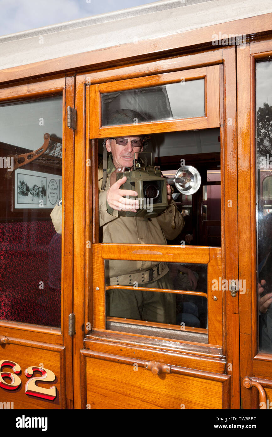 Un 1940's costume weekend a Weybourne UK. Un soldato prende una fotografia attraverso un carrello ferroviario finestra Foto Stock