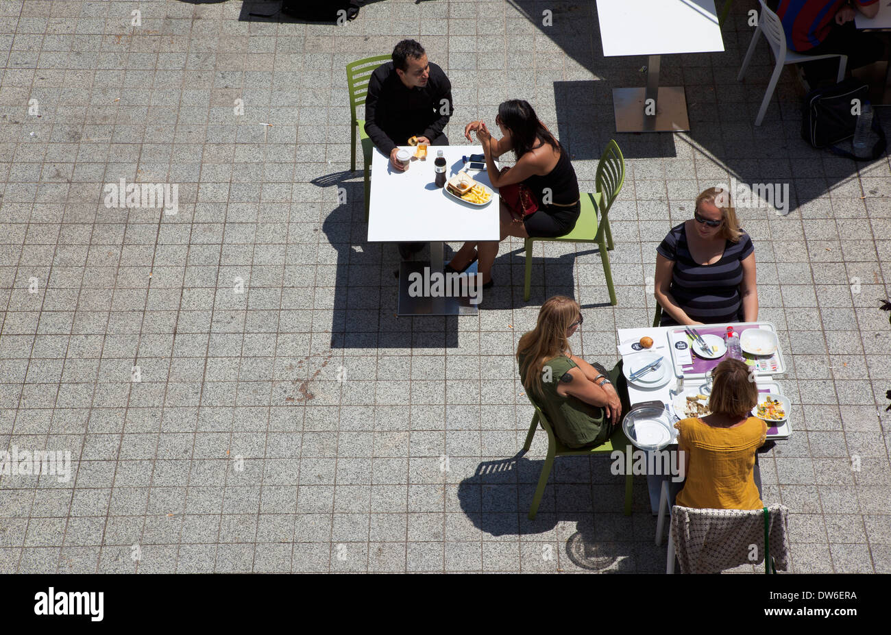 In Spagna, in Catalogna, Barcellona, persone sat avente il pranzo al di fuori nella piazza del World Trade Center. Foto Stock