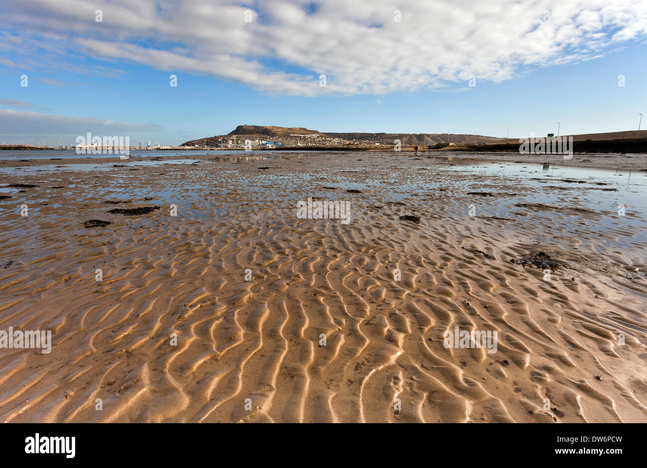 Sentieri di sabbia alta illuminata dalla luce del sole che conduce verso l'isola di Portland nel Dorset in corrispondenza di un eccezionalmente bassa marea Foto Stock