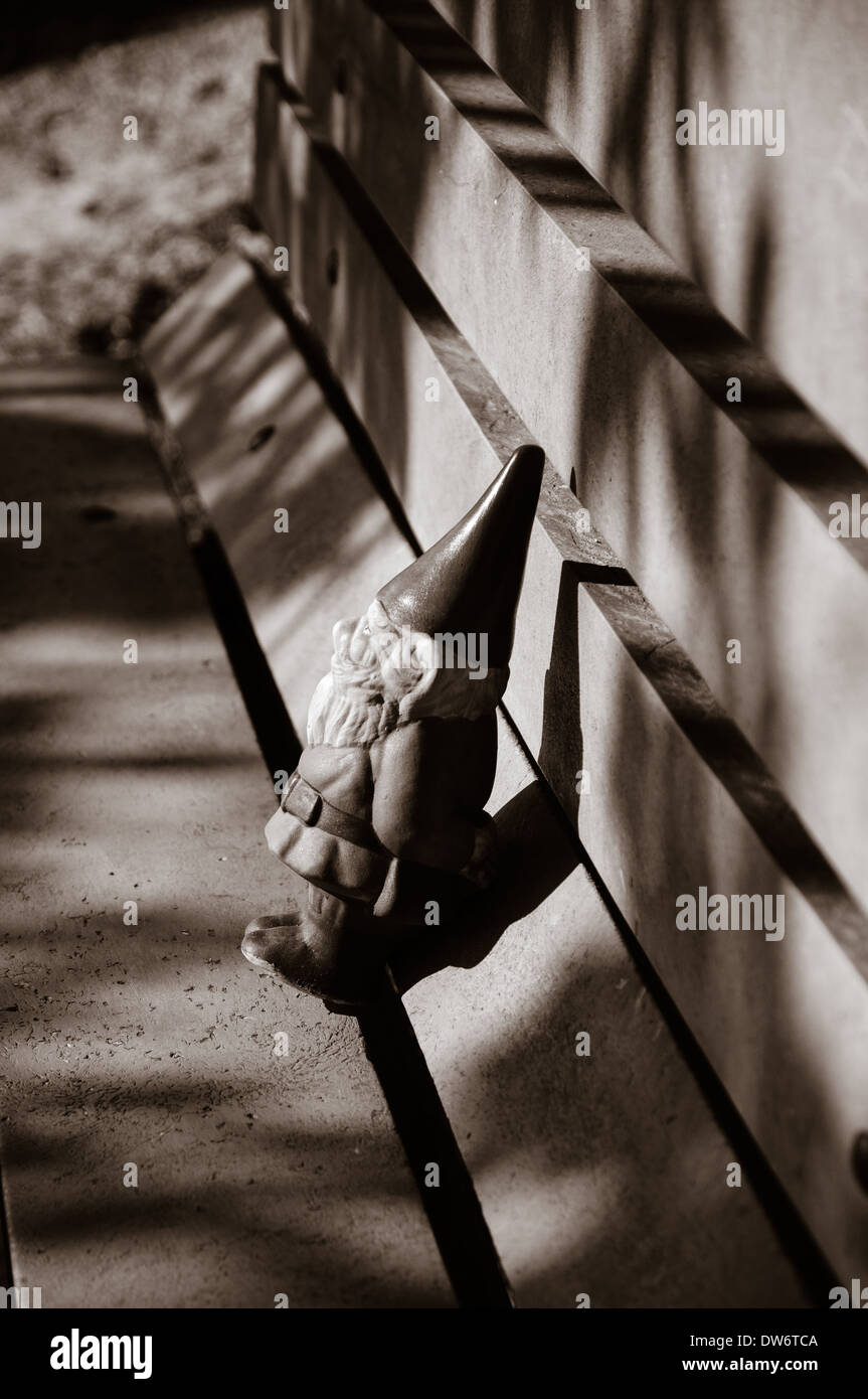 Immagine in bianco e nero di un piccolo gnomo da giardino su un banco di lavoro Foto Stock