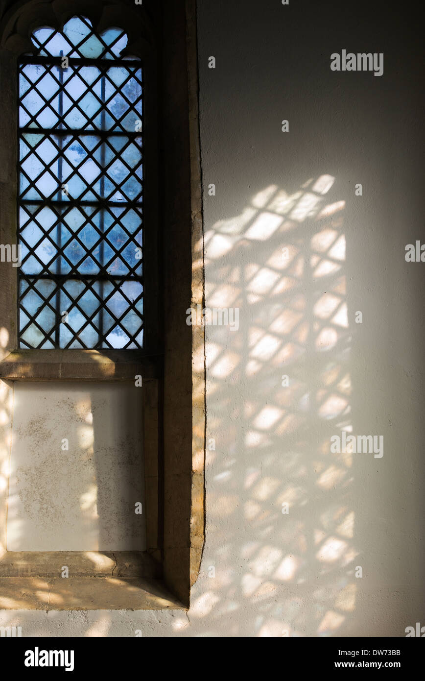 Diamond leaded windows in una chiesa con la luce del sole e ombre. Regno Unito Foto Stock