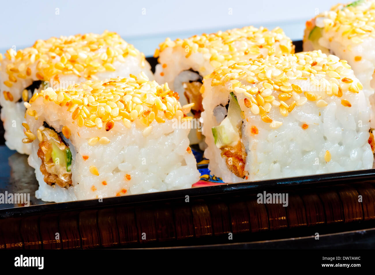 Rulli con anguilla e semi di sesamo su un piatto nero Foto Stock