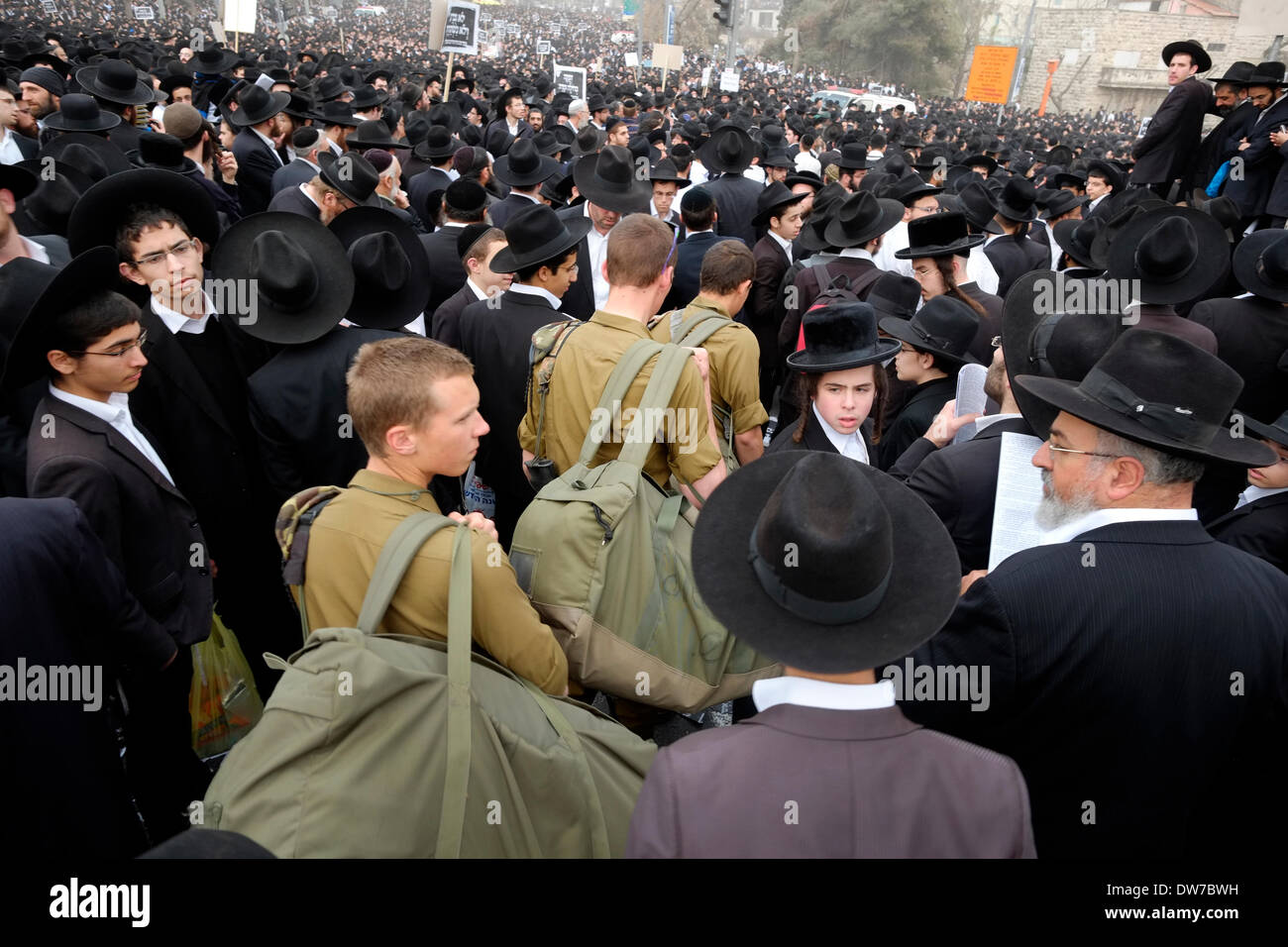 Soldati israeliani spingendo il loro modo attraverso una folla di dimostranti durante una protesta di massa di ultra-Ebrei Ortodossi enraged oltre i piani per il loro reclutamento di giovani uomini per il servizio militare in Gerusalemme ovest Israele il 02 marzo 2014. La massiccia manifestazione si è tenuta contro un disegno di legge che aumenterebbe il servizio militare tra i membri di Israele la ultra-ortodosse. Organizzatori fatturati l'evento come un 'million-uomo protesta' Foto Stock