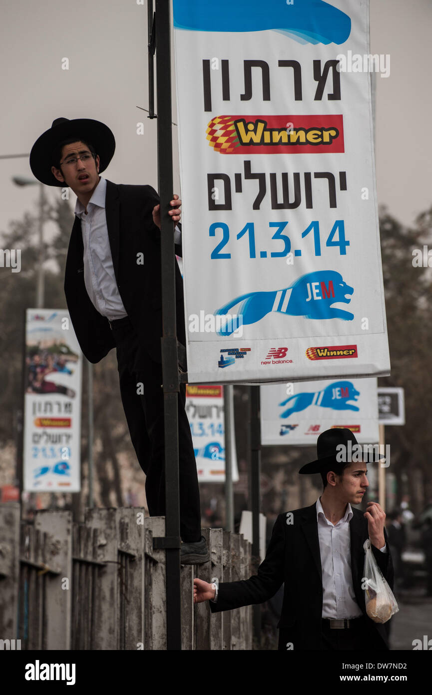Gerusalemme. 2 Mar 2014. Gli Ebrei Ultra-Orthodox stare accanto a una maratona di Gerusalemme banner durante una massa anti-progetto di rally in Gerusalemme, 2 marzo 2014. Centinaia di migliaia di ultra- ebrei ortodossi raccolse Domenica a Gerusalemme per protestare contro un piano del governo per arruolare i loro giovani nell'esercito. Il governo sta spingendo per un progetto di legge di reclutamento ultra-ortodossi e mettere le sanzioni penali, compresa la detenzione, su progetto di dodgers. Credito: Li Rui/Xinhua/Alamy Live News Foto Stock