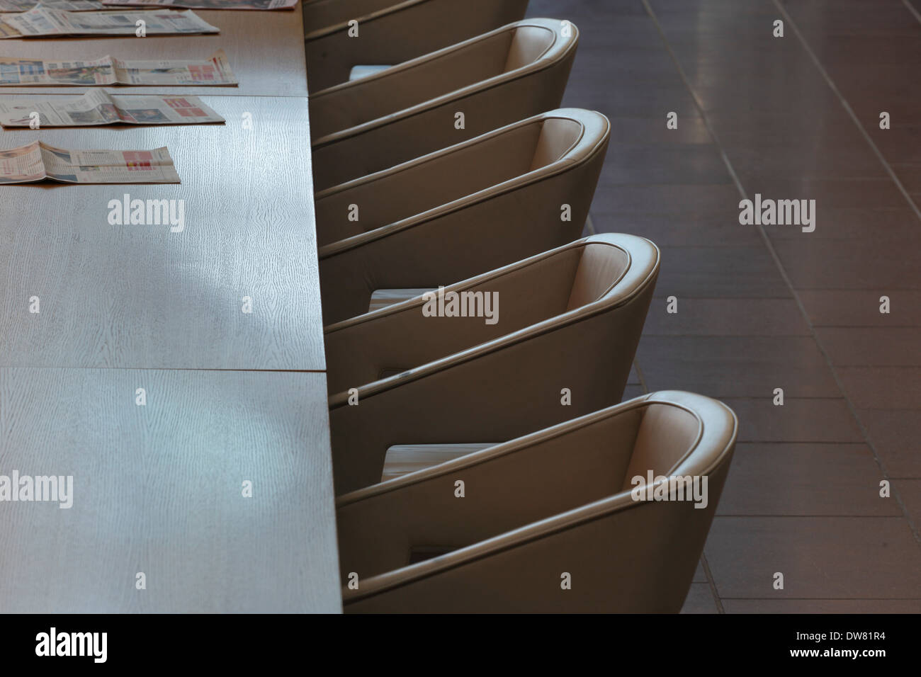 Genk biblioteca pubblica, a Genk, in Belgio. Architetto: Claude Vasconi, 2008. Sedie e tavolo con quotidiani in luce del sole di mattina. Foto Stock