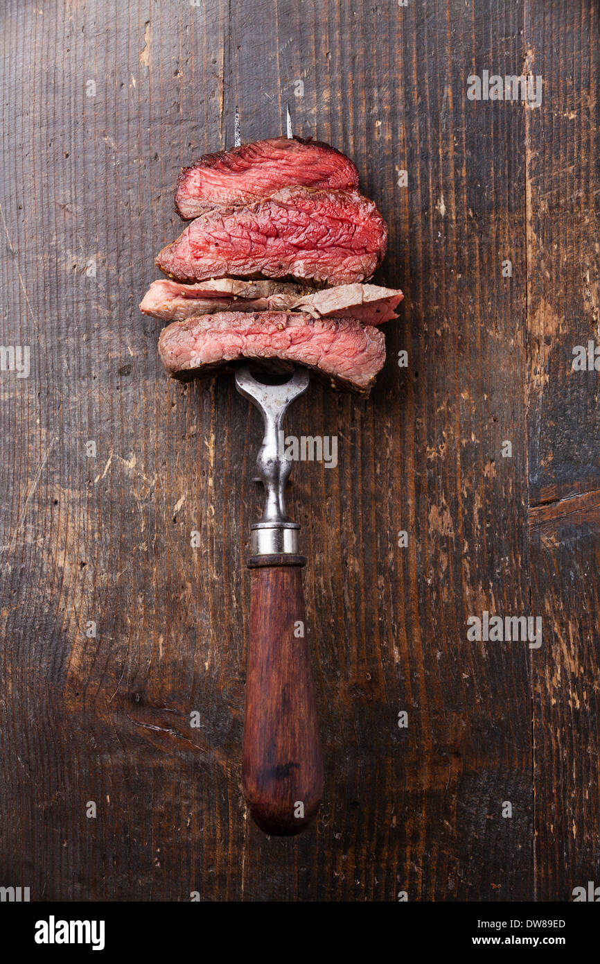Fette di carne di manzo sulla carne forcella sullo sfondo di legno Foto Stock