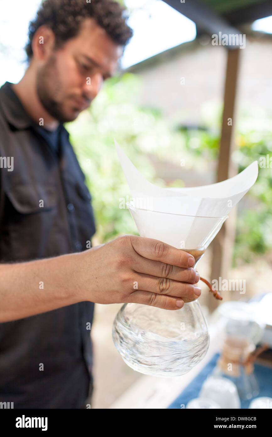 Il lavaggio del filtro di carta prima di preparare una tazza di fresco usando una macchina per caffè Chemex presso un impianto di tostatura in Juayua El Salvador Foto Stock