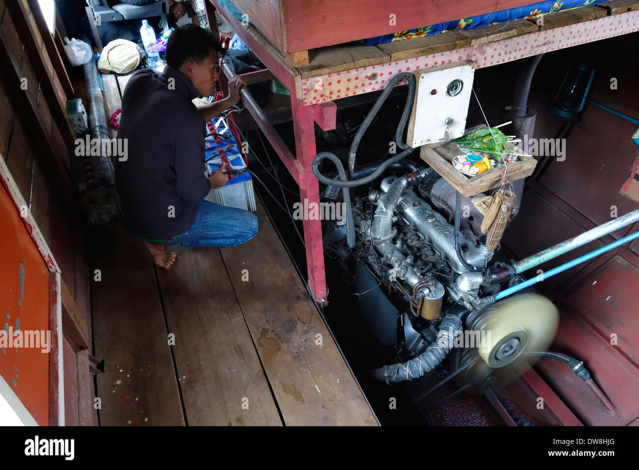 Membro di equipaggio il monitoraggio del motore di un 'slow' in barca sul fiume Mekong in Laos. Foto Stock
