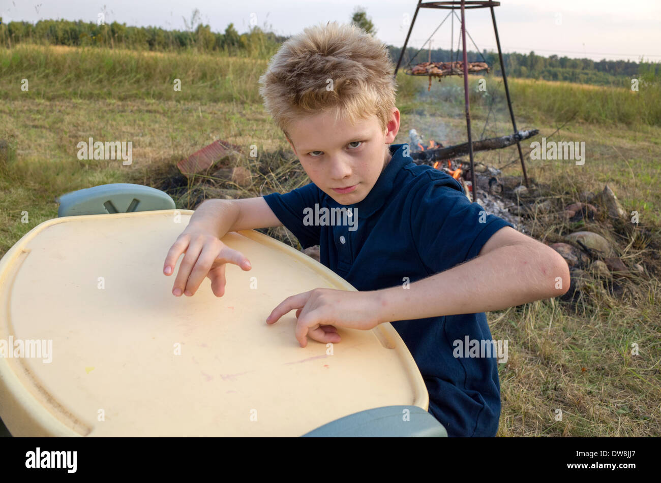 Ragazzo polacco età di dieci anni suona la batteria sul tavolo per bambini durante un barbecue di famiglia. Zawady Polonia centrale Foto Stock