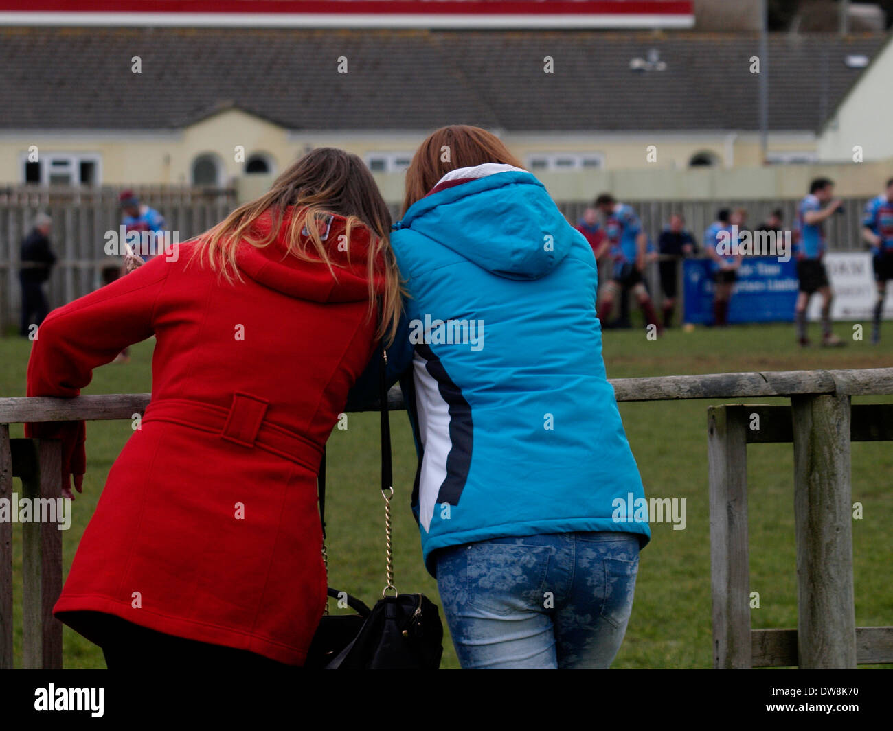 Due giovani donne di guardare una partita di rugby, Bude, Cornwall, Regno Unito Foto Stock