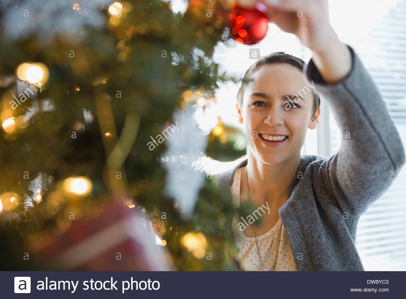 Donna decorare albero di Natale a casa Foto Stock