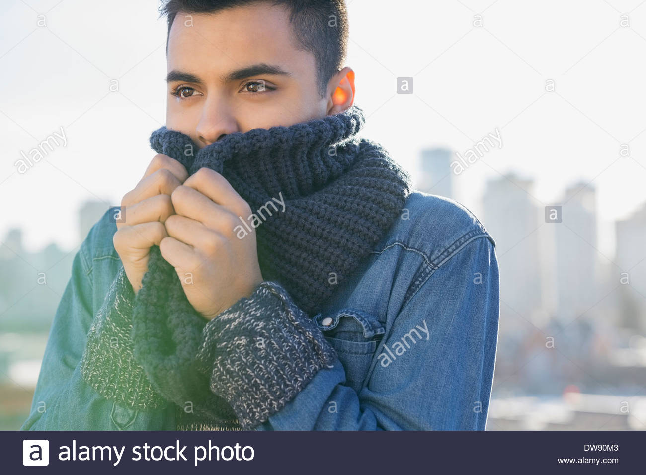 Uomo in piedi all'aperto con un accogliente sciarpa lavorata a maglia Foto Stock