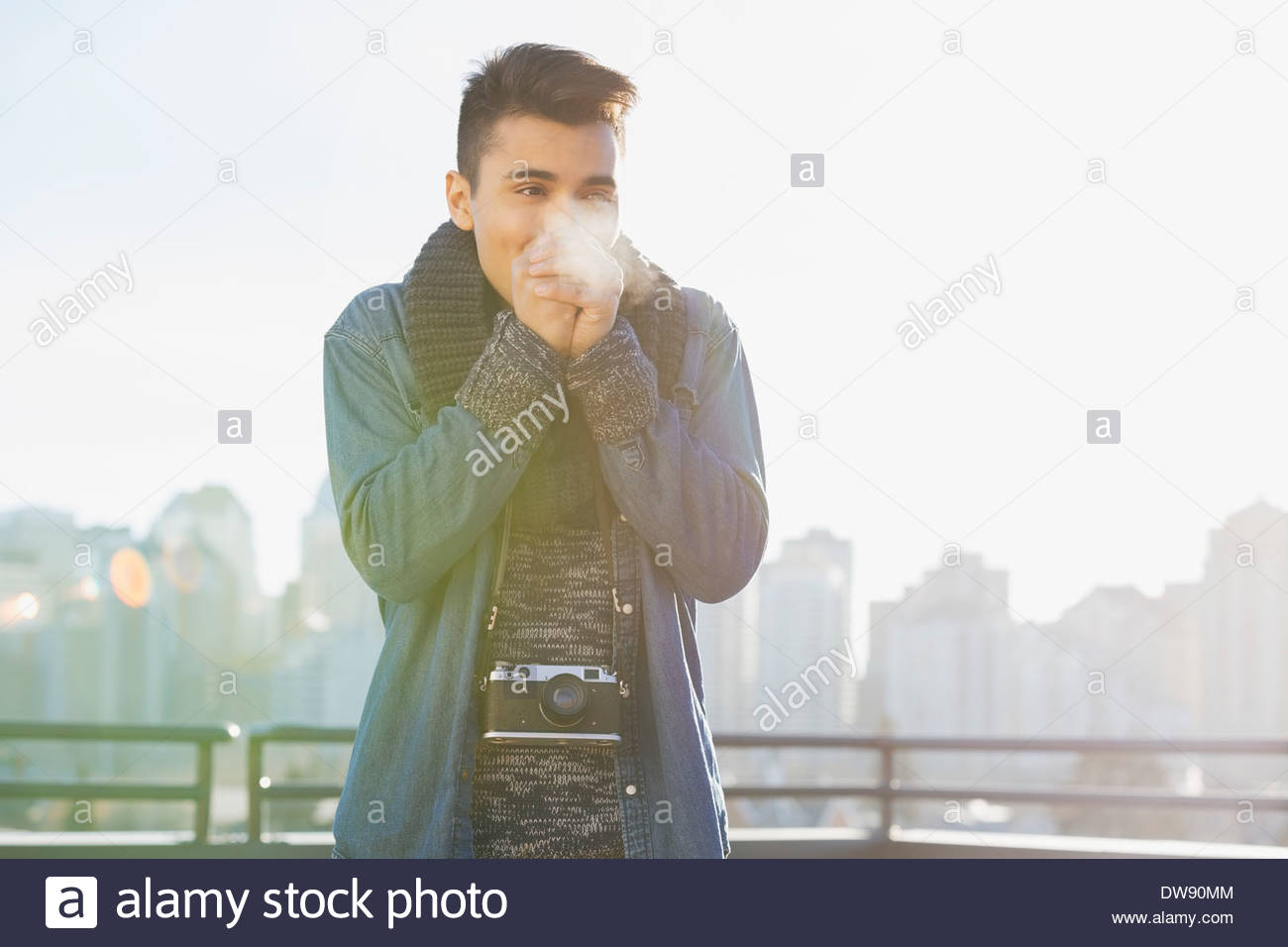 Uomo in piedi all'aperto mani di riscaldamento in inverno Foto Stock