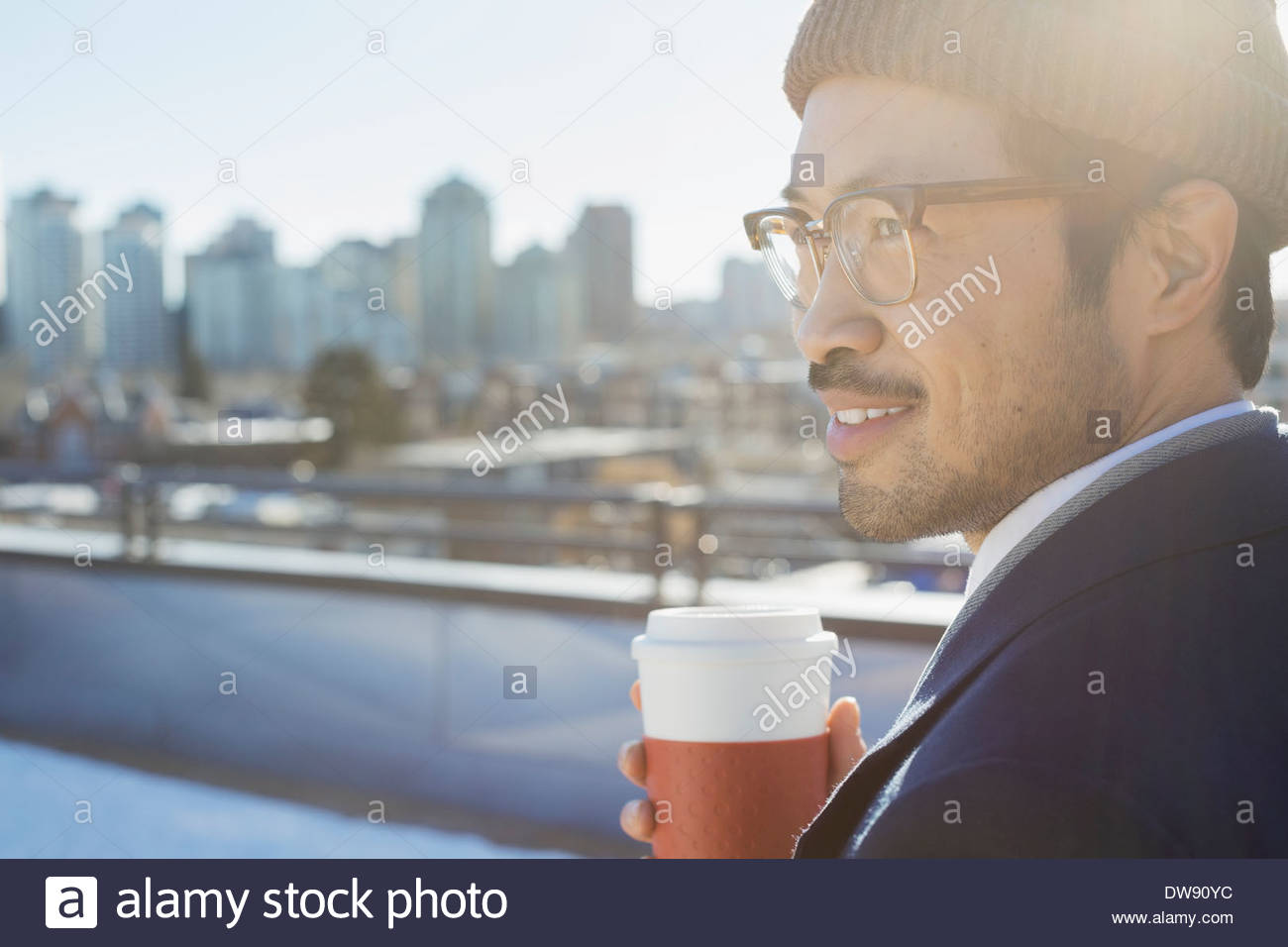 Riflessivo uomo con tazza monouso sul patio Foto Stock