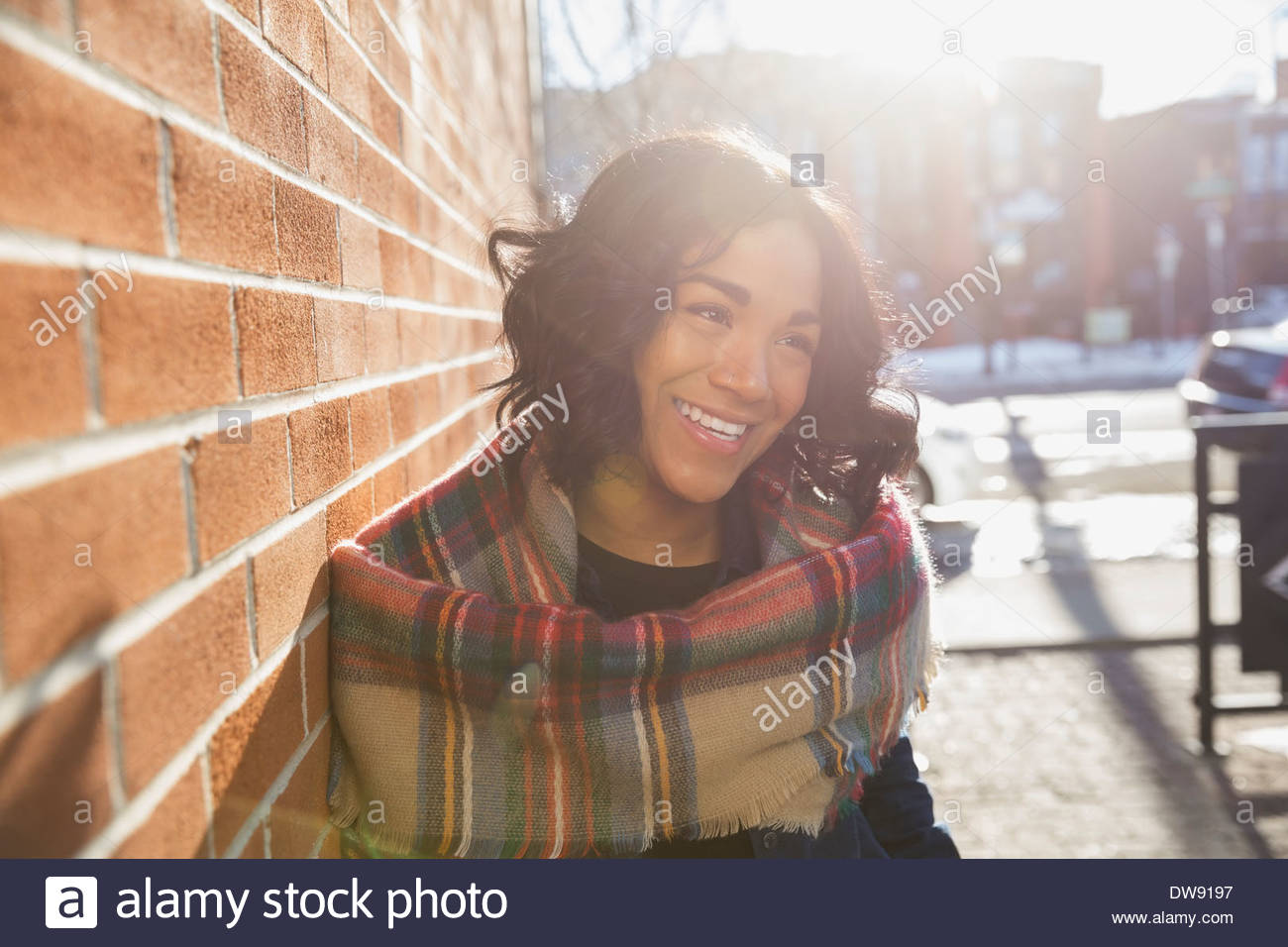 Donna sorridente in piedi da un muro di mattoni Foto Stock